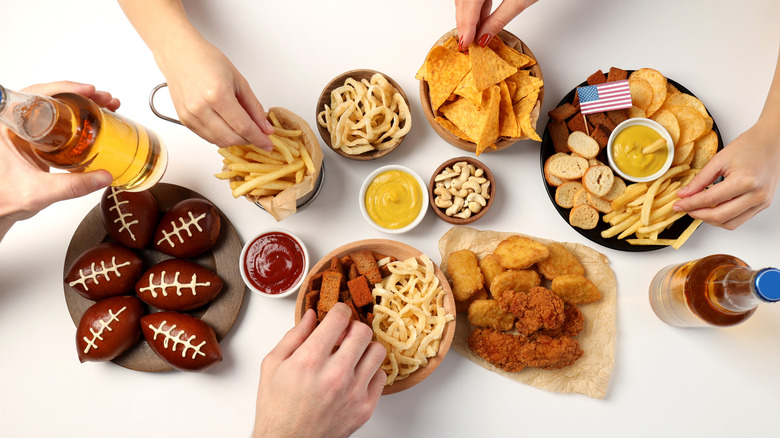Hands reaching for Super Bowl-themed snacks