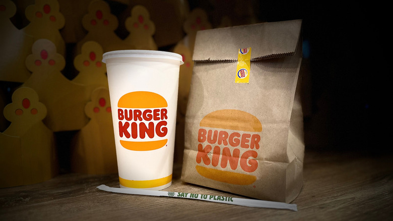 A Burger King bag, drink, and straw sit on a table