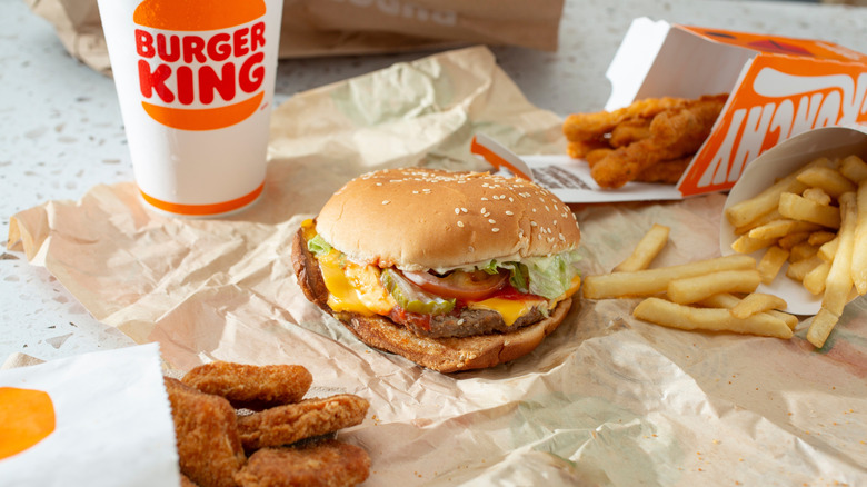 Burger King food with a Whopper, chicken fries, fries, and nuggets laid out.
