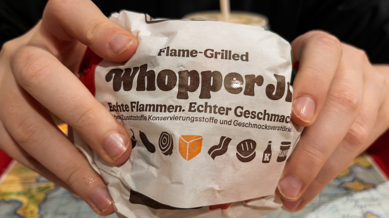 Hands holding a Whopper Jr. at Burger King.