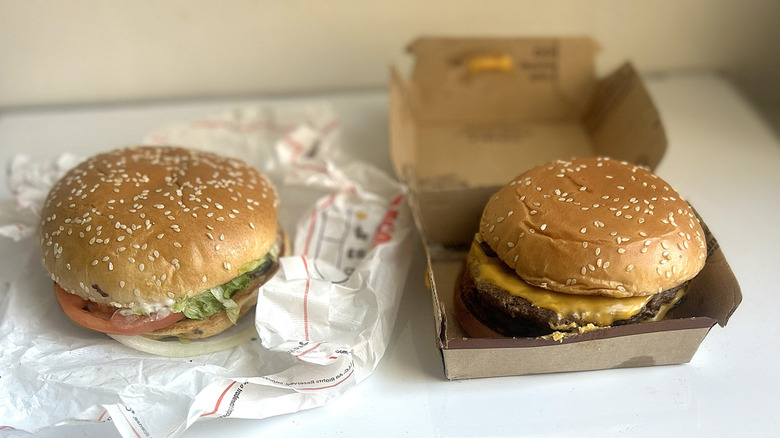 The McDonald's Quarter Pounder side by side with the Burger King Whopper on a table, unpackaged.