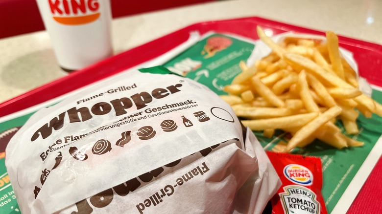 Burger King Whopper with fries and drink in background