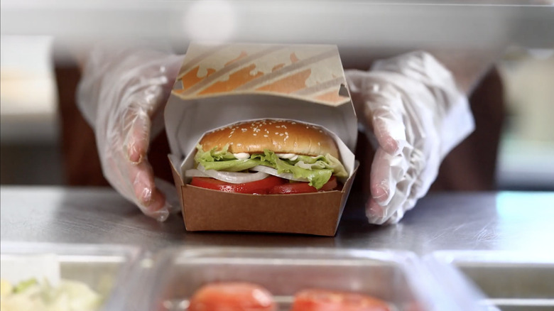 hands preparing whopper in cardboard box