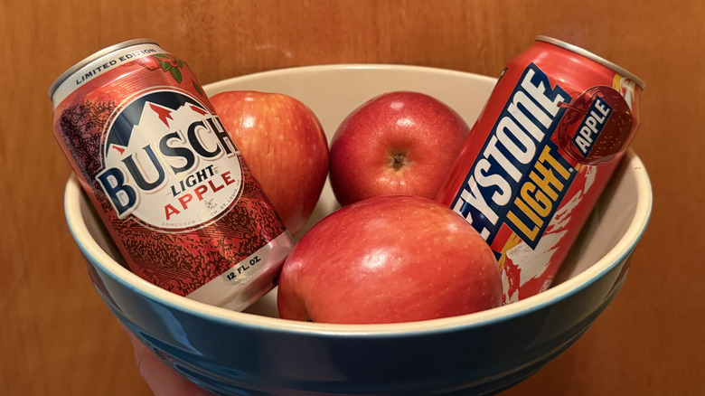 the two apple beers sit in a bowl with apples