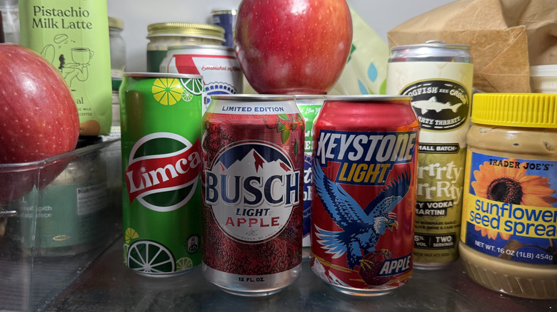A fridge filled with apple beers, apples and such