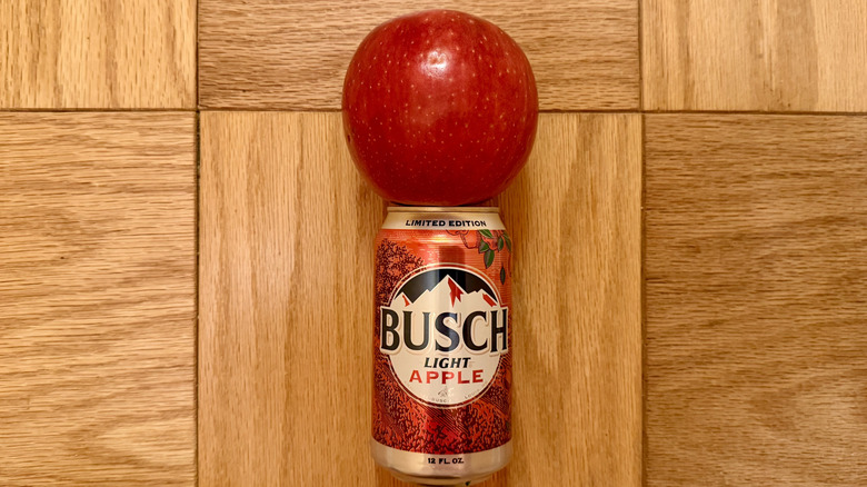 a can of Busch Light Apple is perched below an apple