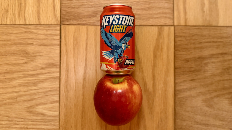 a can of Keystone Light Apple sits atop an apple