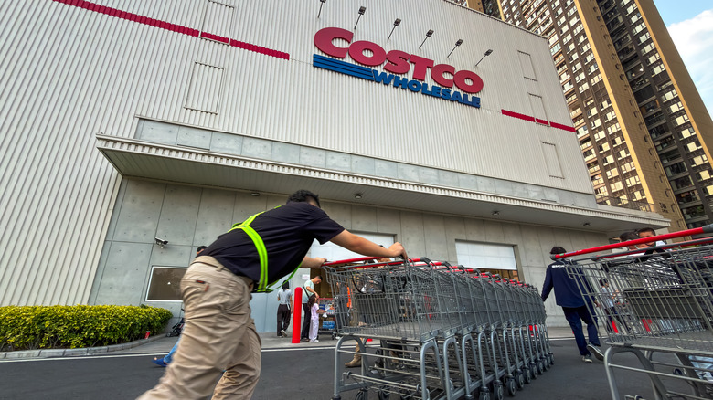 A worker pushing a train of shopping carts outside of a Costco Wholesale location