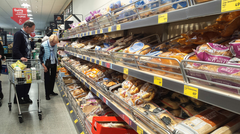 Bakery section in Aldi supermarket showing food goods for sale with customers browsing in the background