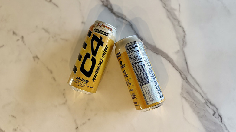 Two cans of C4 All Hopped Up lying on marble countertop, one showing front of can and the other showing nutrition label