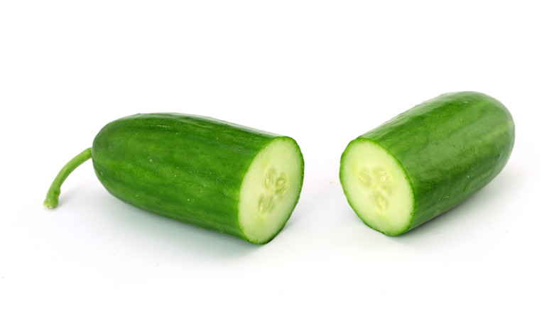 Two halves of a fresh cucumber with glossy green skin and visible seeds, placed on a white background.