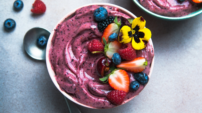Acai bowl with berries, cherries, and flowers