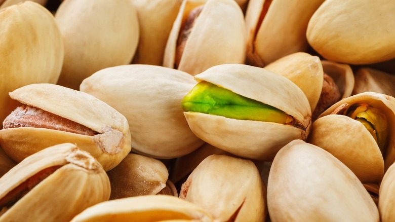 A close-up shot of green and brown pistachio nuts in shells