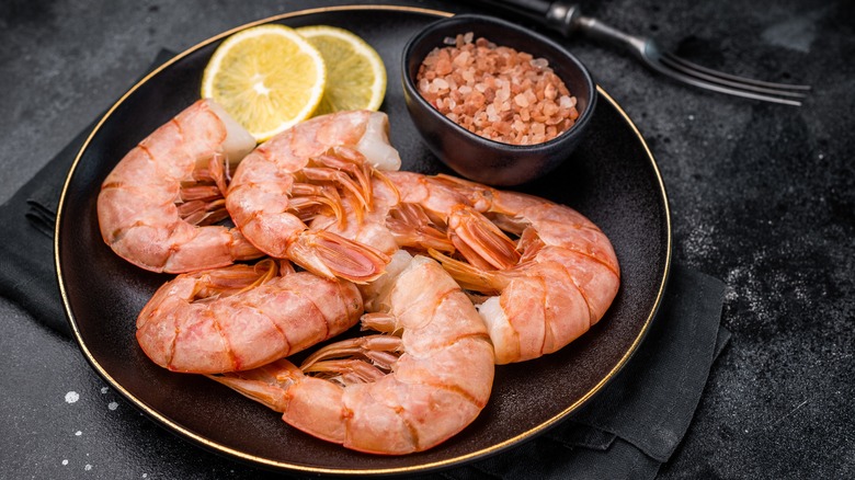 a plate of raw, headless shrimp on a black plate