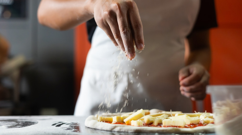 Hands assembling pizza on fresh dough