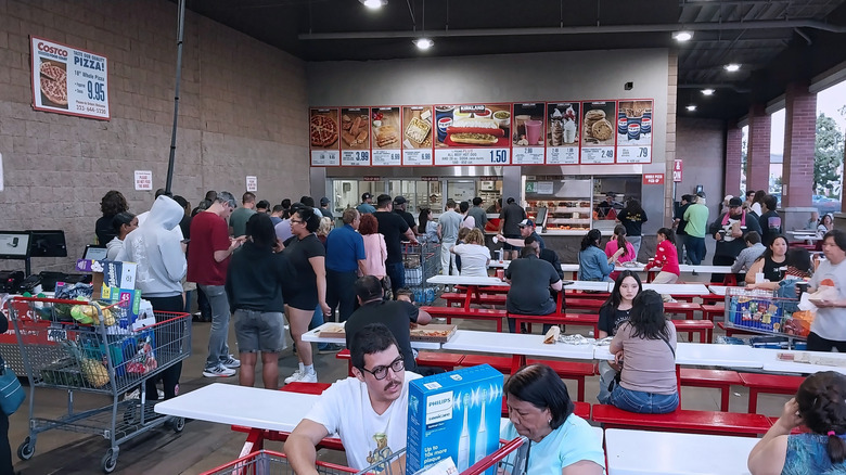An outdoor costco food court with a long line of people waiting to order