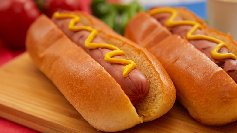 A hot dog in a bun with mustard.