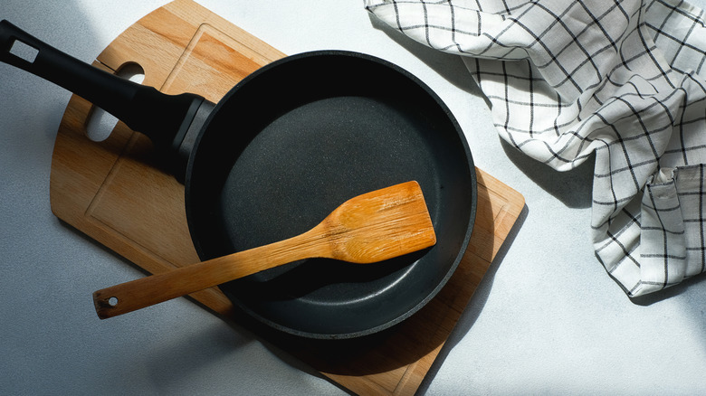 A clean cast iron pan with a wooden spoon and a towel
