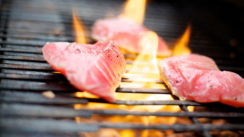 Three pieces of tuna on a fiery grill.