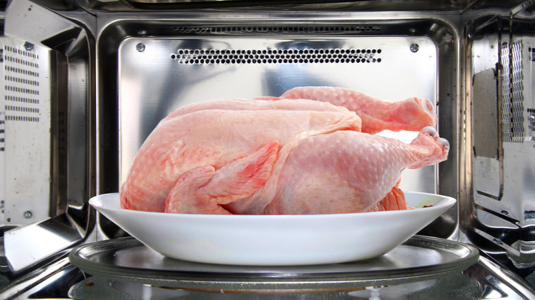 A raw whole chicken is shown inside a microwave