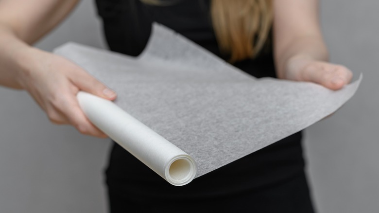 Person unrolling parchment paper