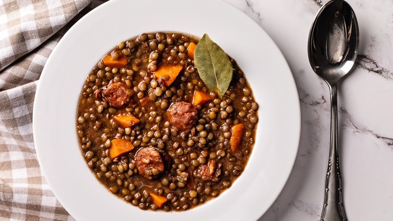 Bowl of lentil soup next to a spoon.