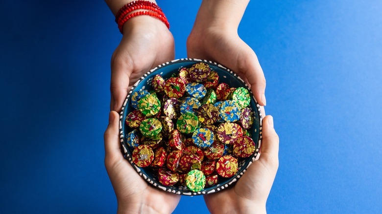 Two pairs of hands holding a bowl of candy