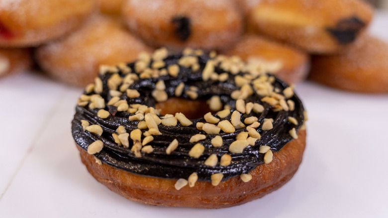crushed nuts on a choclate iced donut