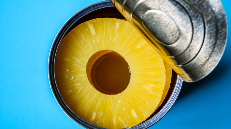 An open can of pineapple on a blue surface
