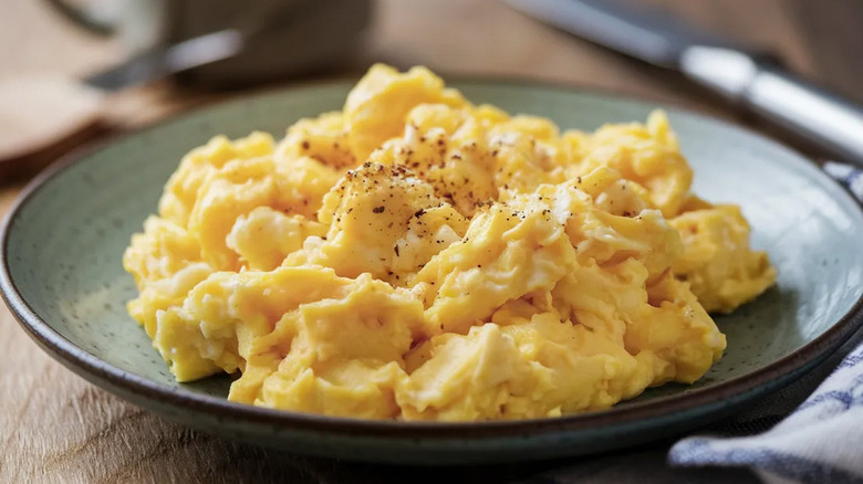 A plate with lightly seasoned scrambled eggs loaded on top of it