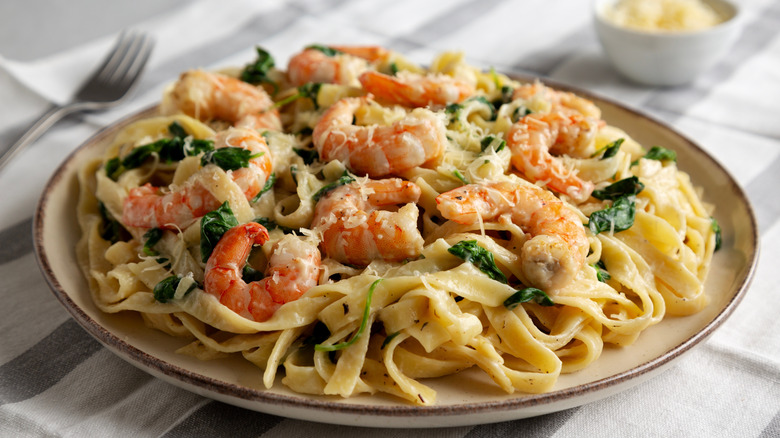 A plate of pasta with shrimp and spinach.