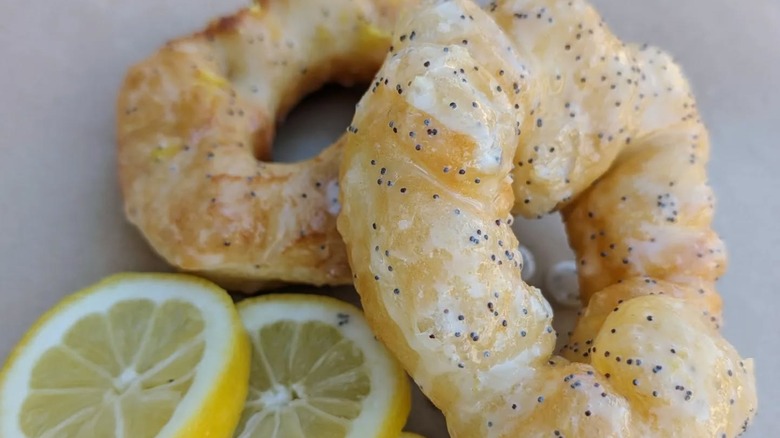 Two Handmade Lemon Poppyseed Doughnuts with fresh lemon slices at Hole Doughnuts.