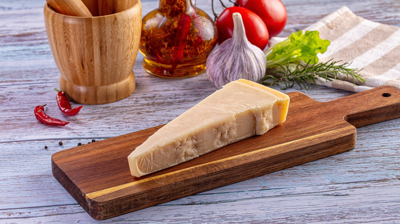 Italian cooking ingredients including Parmesan and chili-infused oil, displayed on a wooden surface and a chopping board