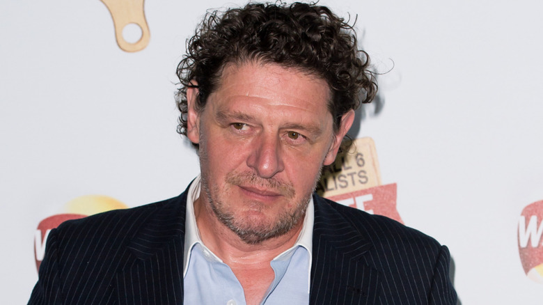Marco Pierre White wears a suit jacket and blue shirt at an event