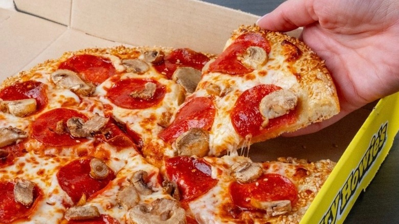 hand getting slice of pizza