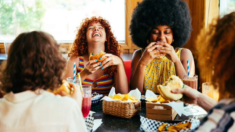 Group of people eating burgers around a table