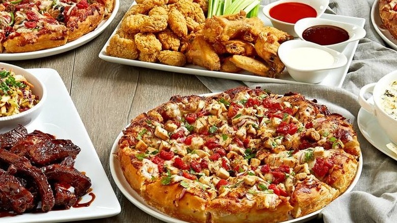 Plates with pizzas, veggies, and ribs