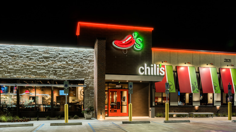 The exterior of a chili's location with neon lights illuminating it at night.
