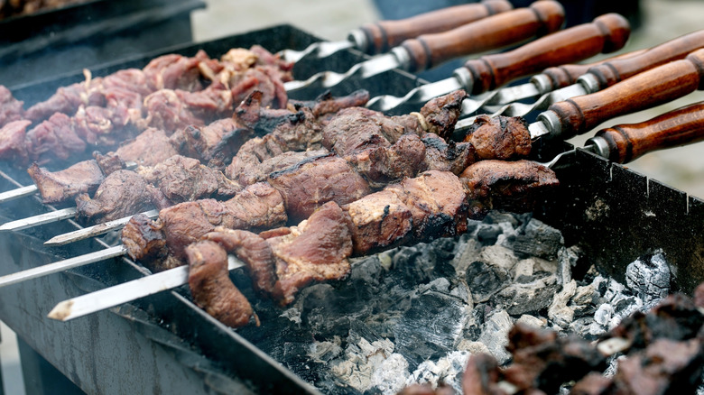 Barbecue meat on skewers over coals