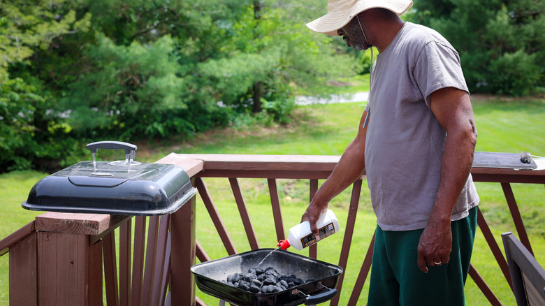 Man using lighter fluid on a grill