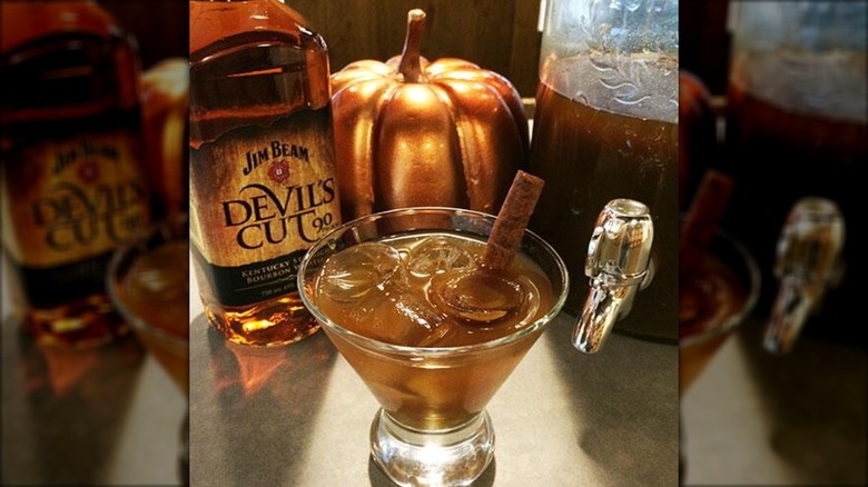 Bottle of Jim Beam Devil's Cut with ice-filled whiskey glass and cinnamon stick