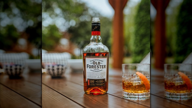 Bottle of Old Forester next to glass of bourbon with orange