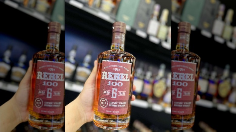 Hand holding bottle of Rebel 100