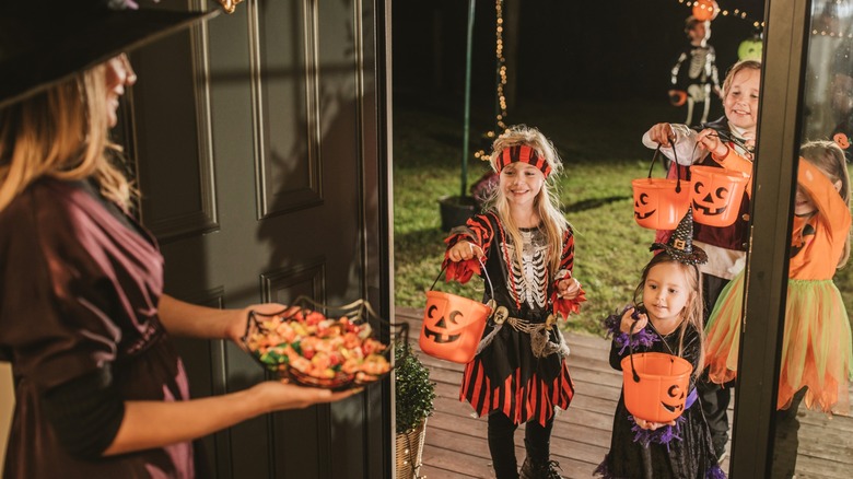 Children at a person's door trick-or-treating on Halloween at night