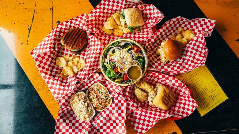 A selection of sandwiches and sides on red checkered paper, shot from above