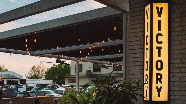 A building with a large patio and a vertical light-up sign that says VICTORY
