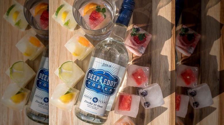 Bottle of Deep Eddy original vodka on table surrounded by fruit and ice cubes