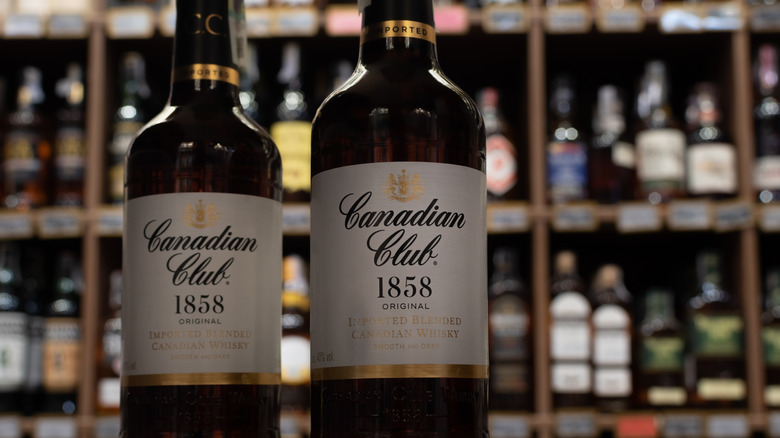 Two bottles of Canadian Club 1858 on a shelf at a store