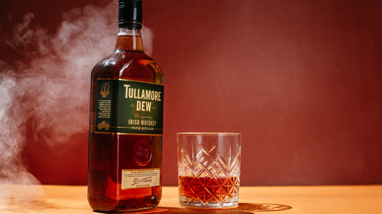Tullamore Dew bottle and whiskey glass in a cloud of smoke
