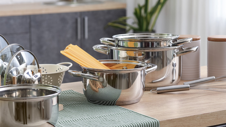 A collection of stainless steel pots, pans, and whisks